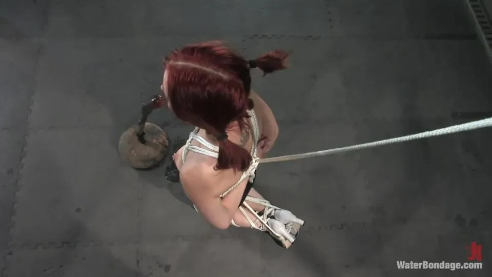 Rope tied redhead sucks on a big black dildo