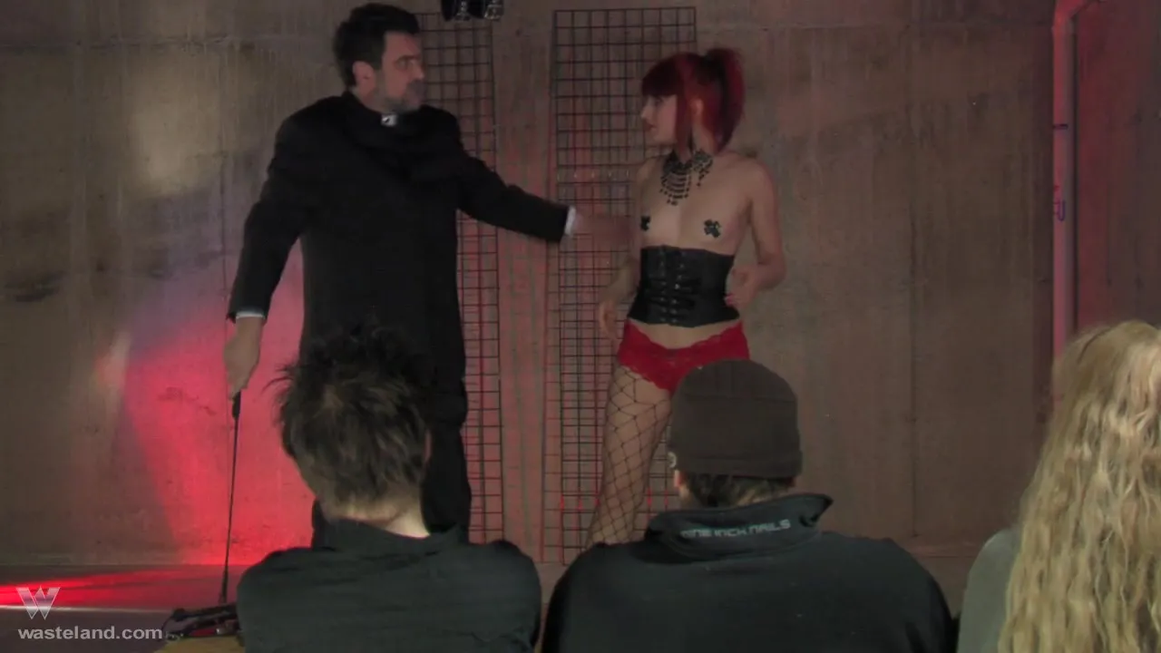 Gorgeous redhead in black corset feels pain during BDSM show