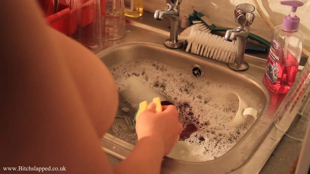 Busty chained chick is washing dishes while been fully naked