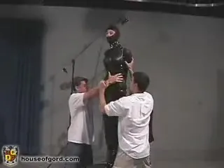 Bitch in latex suit gets prepared for a torture by two masters